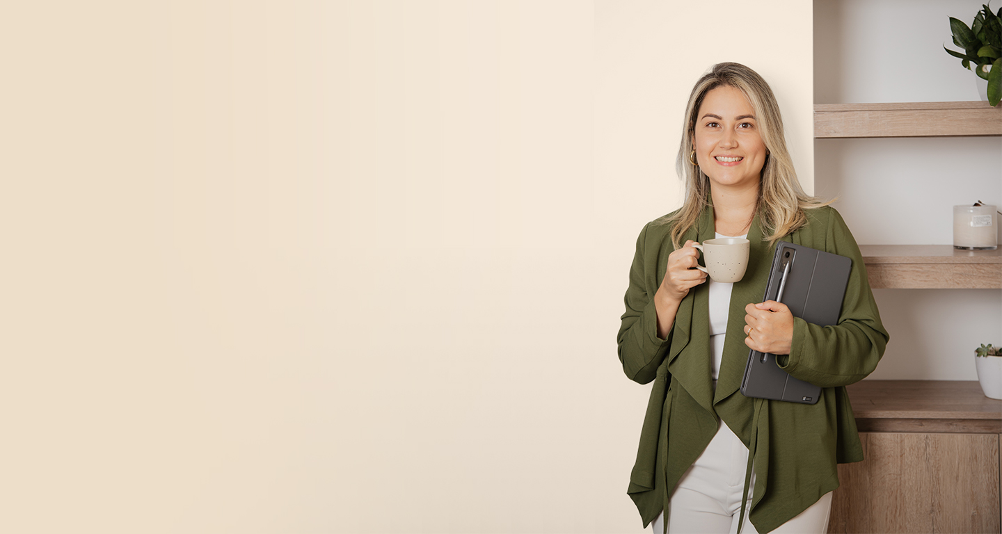 Merly Flórez sonriendo, con una taza en una mano y una tableta en la otra